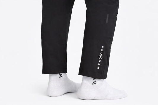 stylish black men’s sports trousers featuring the PRONOAM logo on the upper thigh. The pants have a modern, tapered fit designed for both. athletic performance and casual fashion. Zipper 
