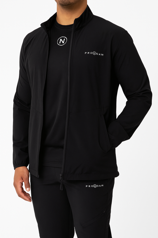 PRONOAM black slim‑tapered sports trousers with white circular N logo on left thigh, premium athletic zippered pockets, tapered ankle‑fit design, and performance sportswear detailing from the PRONOAM Collection — NEW COLLECTION. DNA COLLECTION RUNWAY COLLECTION 