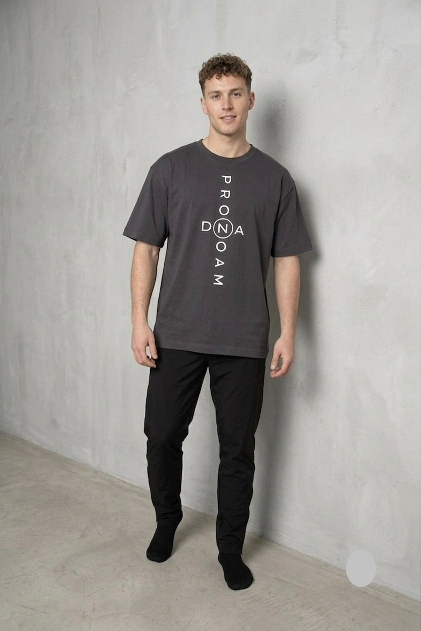 Men’s dark grey oversized PRONOAM T‑shirt with vertical white PRONOAM DNA branding, minimalist street‑luxury design, premium heavyweight fabric, styled with black tapered trousers 
• PRONOAM Vertical Logo T‑Shirt 
“Premium men’s charcoal grey PRONOAM T‑shirt featuring bold vertical PRONOAM branding with circled N emblem, modern streetwear silhouette, paired with black slim trousers 
• PRONOAM Minimalist Dark Grey OVERSIZED T‑Shirt